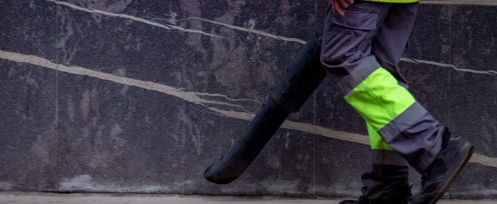 Cleseup worker clean public concrete floor with vacuum cleaner. Worker wear uniform use leaf blower clean sidewalk in the city. Janitor blowing dust on sidewalk. Cleaning city for good hygiene concept